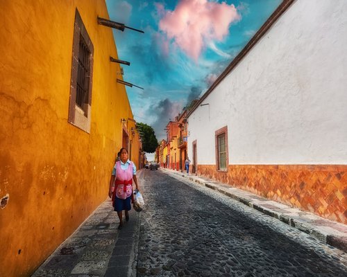 Mujer caminando por una calle soleada empedrada en una colonia de México